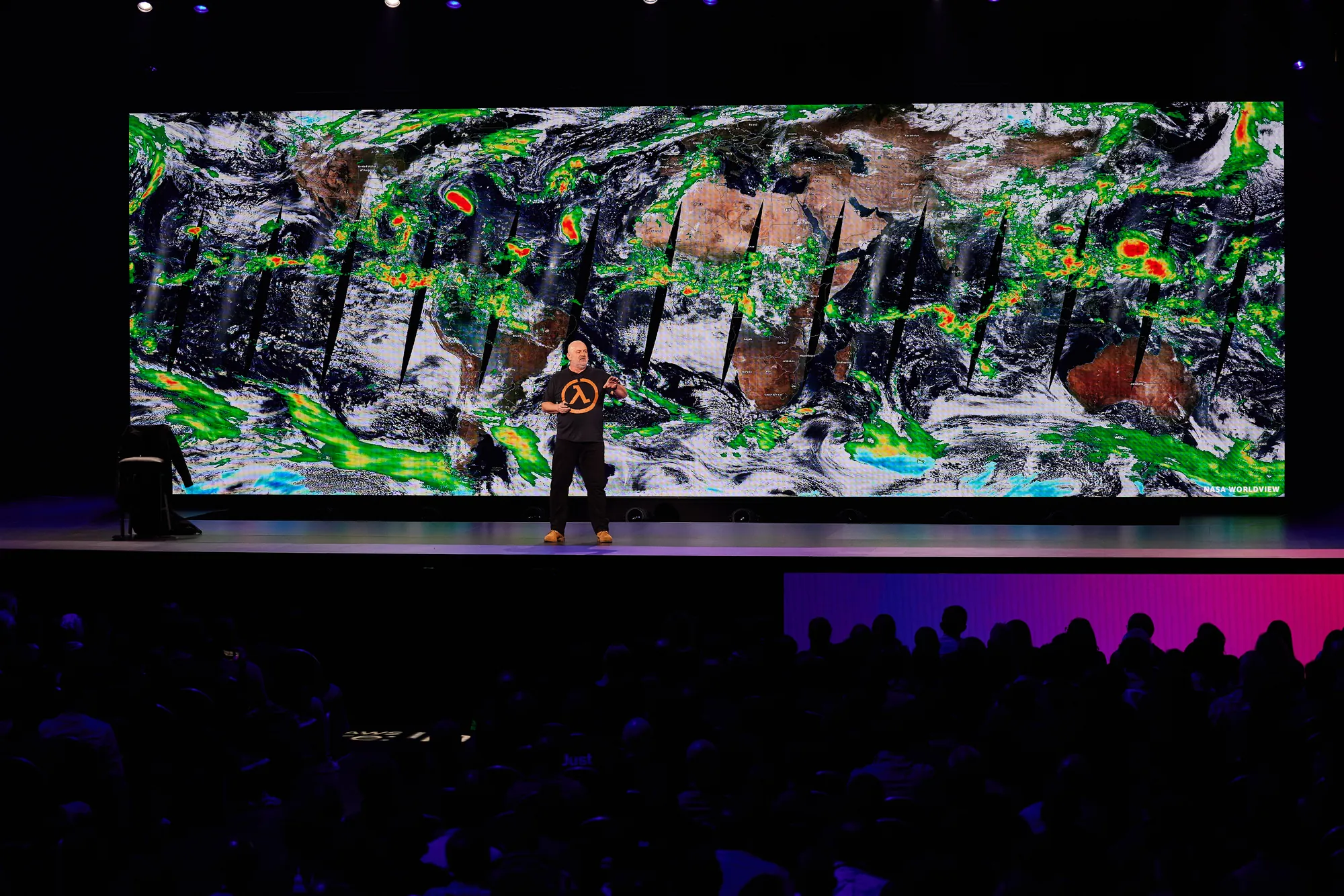Werner Vogels small on the stage below a vast swirling image on the screen