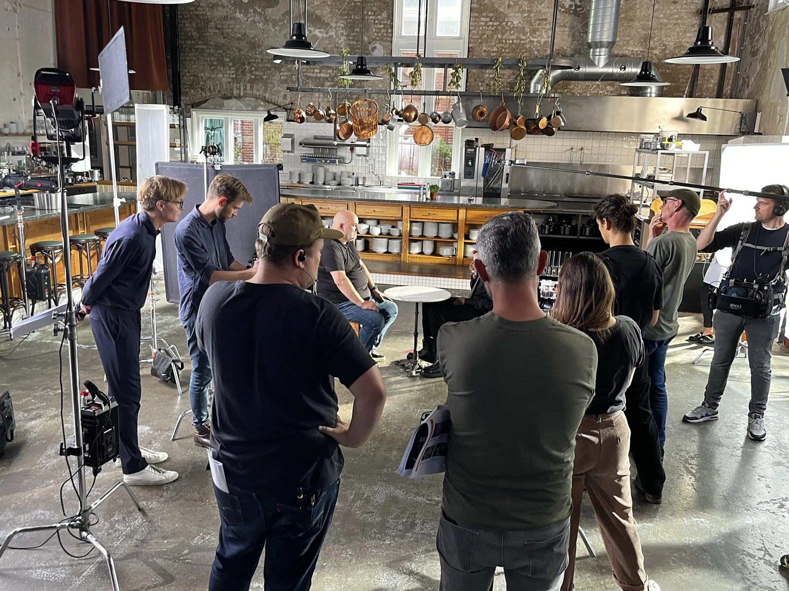 The crew gathered around Dr. Werner Vogels on the set, a restaurant kitchen with copper pans hanging over the counter, in Amsterdam.