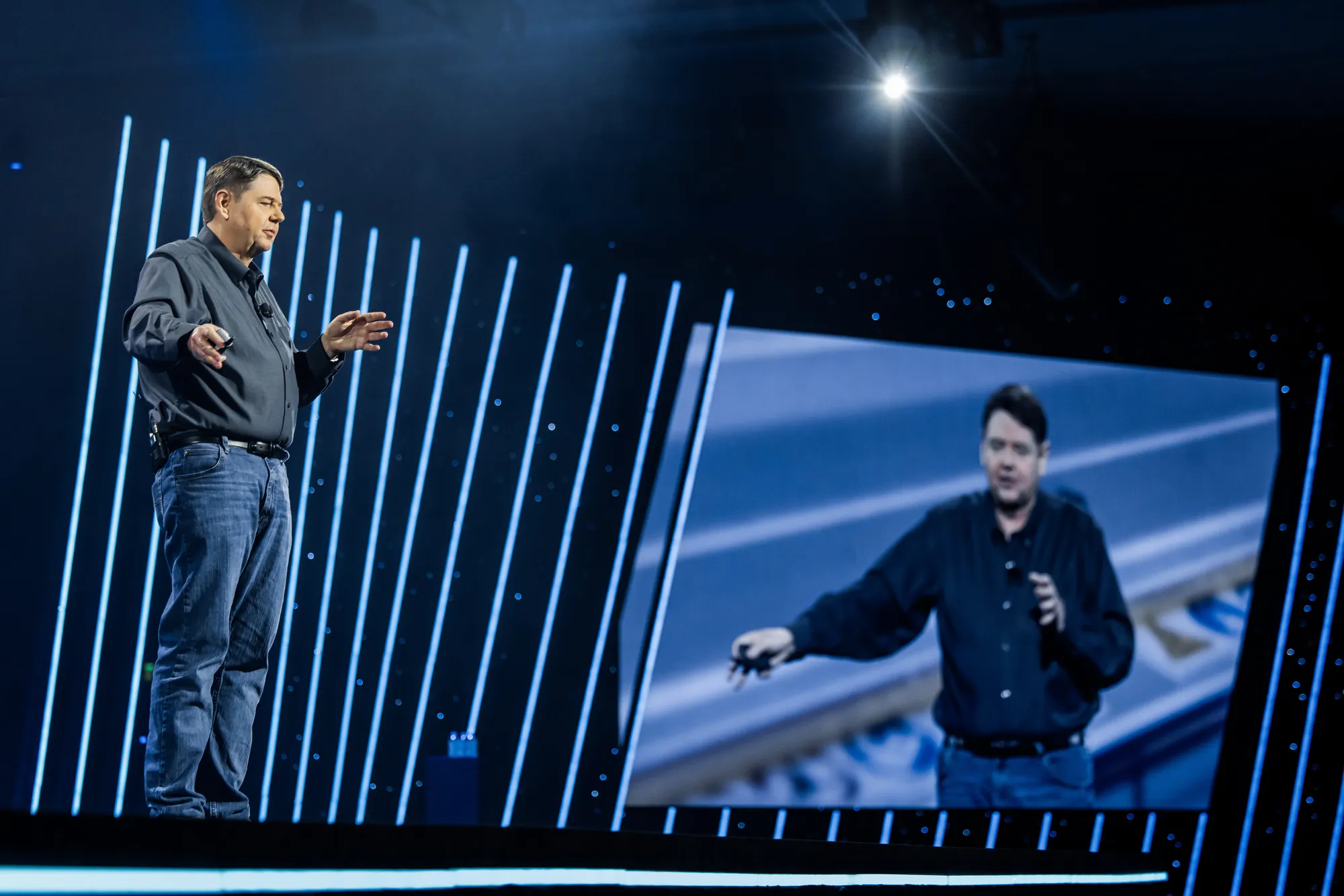 Bill Vass on stage, a giant image of himself on the screen beside him